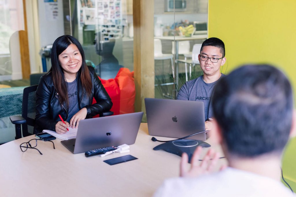 Three people having a lively discussion in a meeting room.